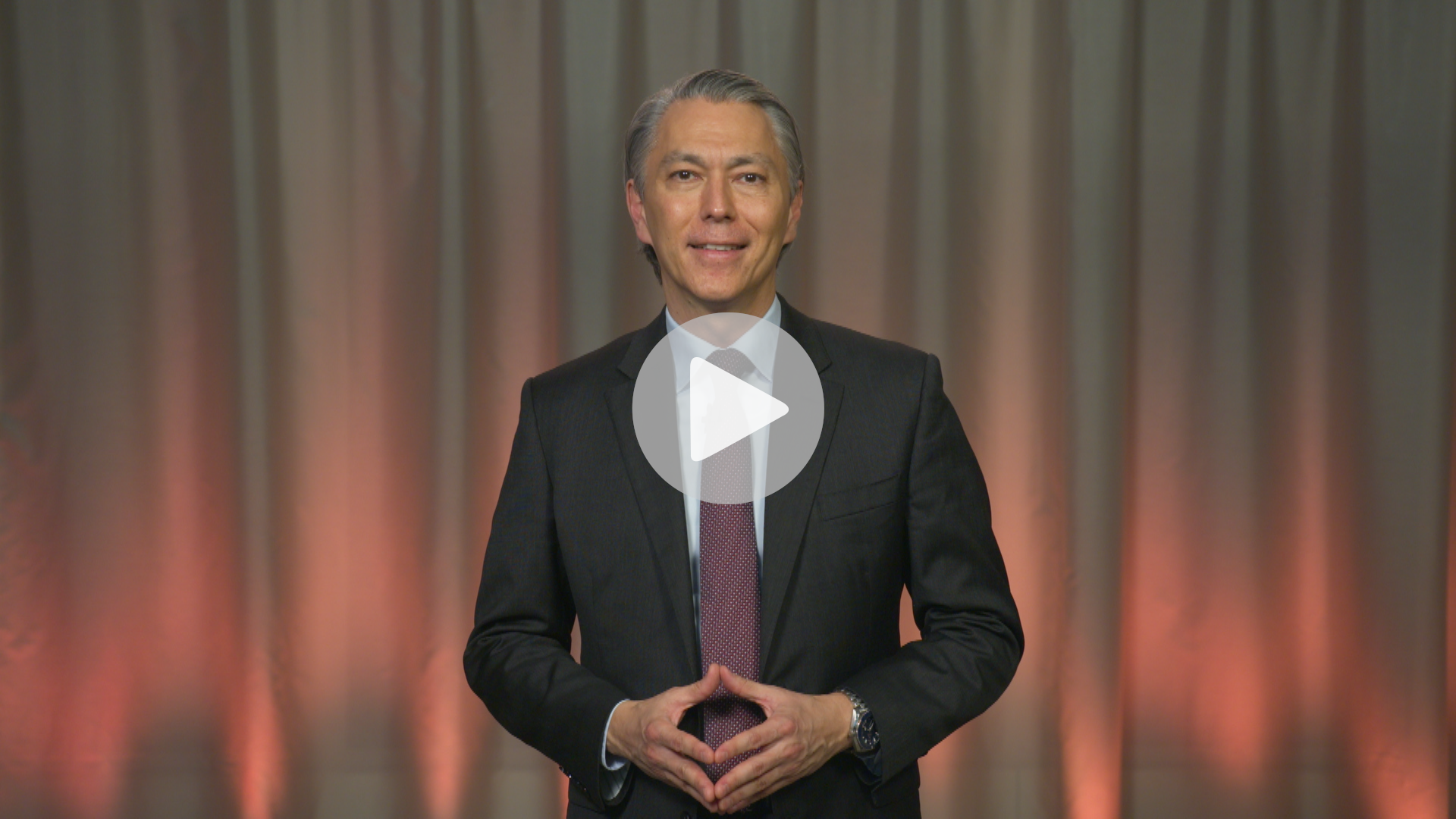 Mike Henry, CEO, standing in dark suit and smiling